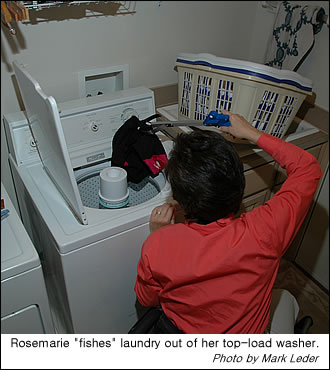 Rosemarie uses a reacher to get laundry out of a upright washer