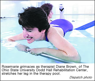 Rosemarie Rossetti grimaces as her leg is stretched by therapist Diane Brown